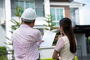 woman and worker looking guy stare at a home as she looks over the aspects of the project that require building permits