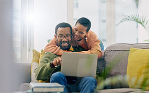 young couple searching for a home use their laptop to explore mortgage tools and mortgage options available to them online