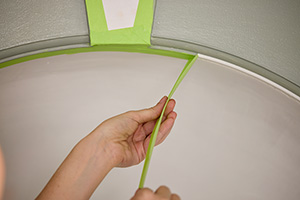 close up view of a DIY painting project focused on removing tape that was used to define a strict border between two paint colors