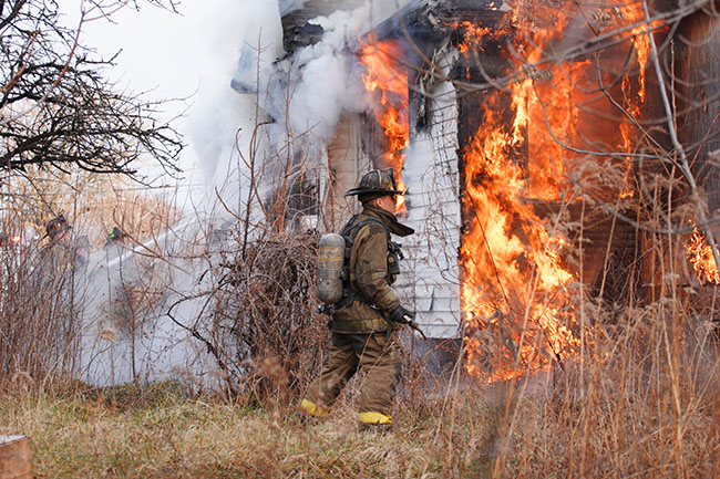 firemen battle a fire in a home as flames continue to consume the structure